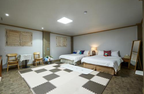 a hotel room with two beds and tables and chairs at Buan Tree California Hotel in Buan