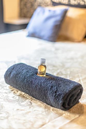 - une couverture bleue sur un lit avec une bouteille de parfum dans l'établissement Studio Baignoire centre ville, à Narbonne