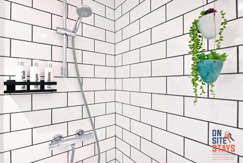 a white tiled bathroom with a shower at OnSiteStays Welling, Modern 2 Bed House, Free Parking & Wifi in Welling