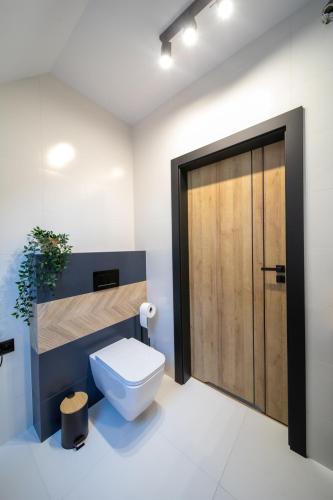 a bathroom with a toilet and a wooden door at Błaż Apart in Laskowa