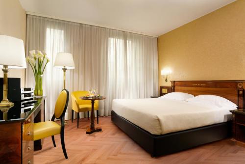a hotel room with a bed and a table and a desk at UNA Hotels Scandinavia Milano in Milan