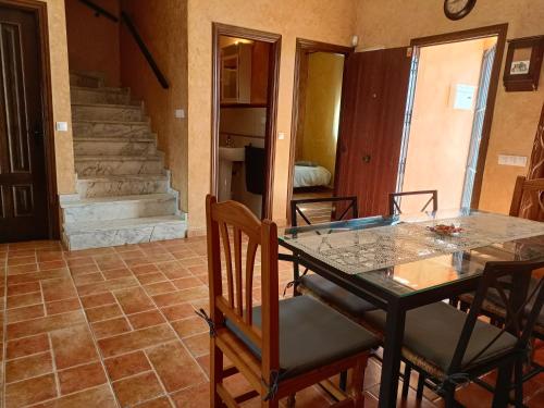 uma sala de jantar com uma mesa de vidro e cadeiras em Casa Puerta de la Sierra em Higuera de la Sierra