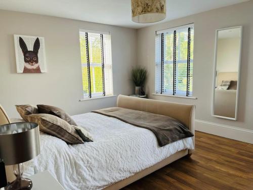 a bedroom with a bed and a lamp and windows at Rayners Farm Lodge in Mattishall