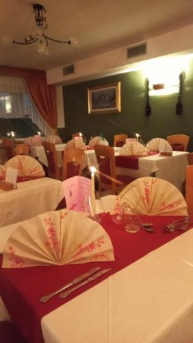 a restaurant with white tables and chairs with red table cloth at Hotel Vigo in Vigo di Fassa