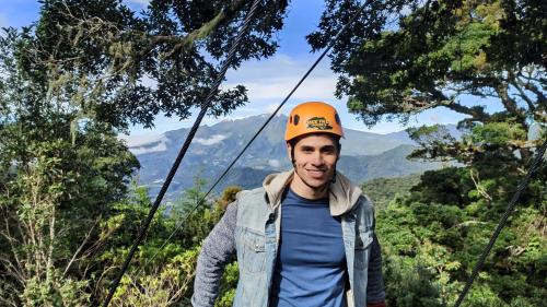 a man in an orange hat standing on a suspension bridge at TREE TREK BOQUETE Adventure Park in Boquete