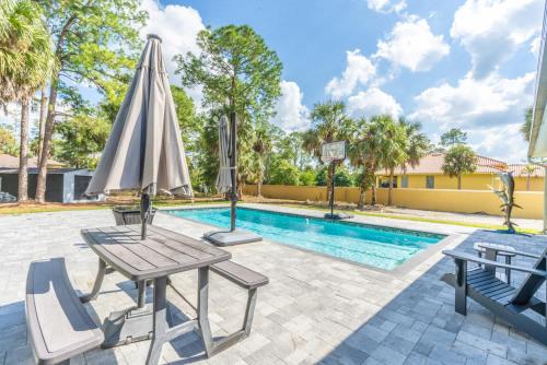 a pool with two chairs and an umbrella and a table at Beautiful Home in Naples with Huge Private Pool in Naples