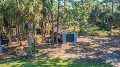 a smallshed in the middle of a yard with palm trees at Beautiful Home in Naples with Huge Private Pool in Naples