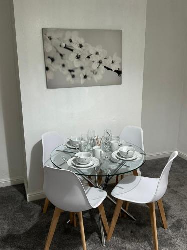 een eettafel met witte stoelen en een schilderij bij Cosy Nest Getaways in Hickleton