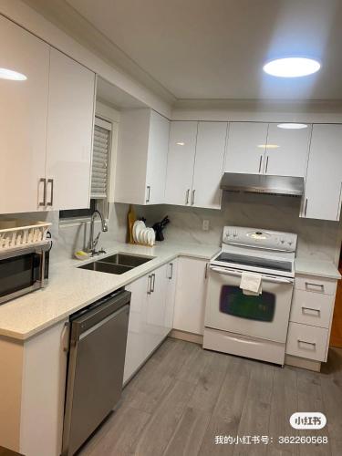 a kitchen with white cabinets and a stove top oven at 佳佳便利民宿C in Vancouver
