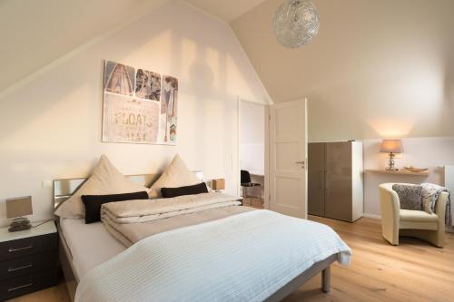 ハイリゲンハーフェンにあるOstsee - Reetdachhaus Nr 4 "Ostseeperle" im Strand Resortの白いベッドルーム(ベッド1台、椅子付)