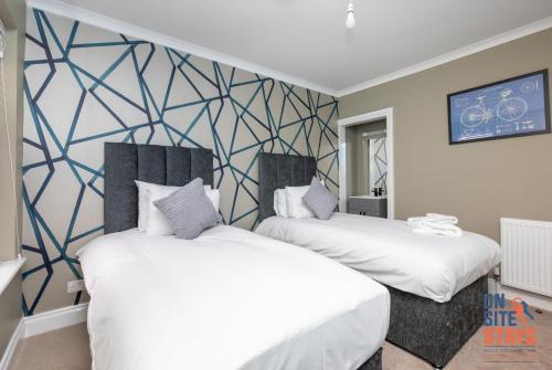 two beds in a room with a wall mural at OnSiteStays - Stylish 4 BR House with Beautiful Outdoor Space, Wi-Fi & Smart TVs in Dartford