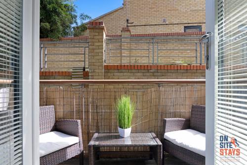 ダートフォードにあるOnSiteStays - Contemporary 2 Bed Apt with Ensuite, 2 x Free Parking Spaces & a Balconyのパティオ(椅子2脚、植物付きテーブル付)