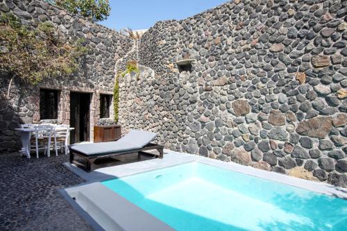 a pool in front of a stone building with a stone wall at Ducato Wine Village in Megalokhori