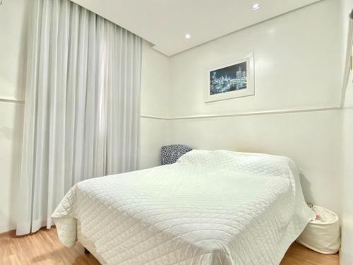 a white bedroom with a bed and a window at Portal do Jaragua in Belo Horizonte