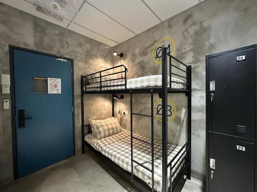 een kamer met 2 stapelbedden en een blauwe deur bij M-Stay Hostel in Chemor