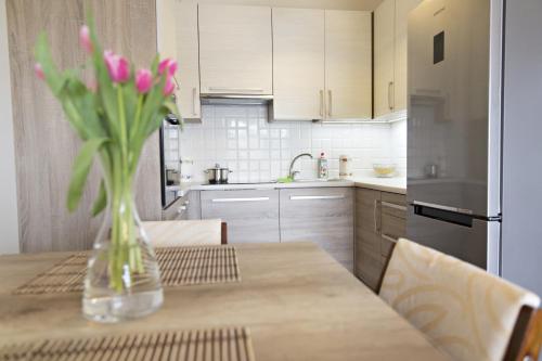 a vase of pink flowers sitting on a table in a kitchen at Apartament MAJA Giżycko Żeglarska in Giżycko