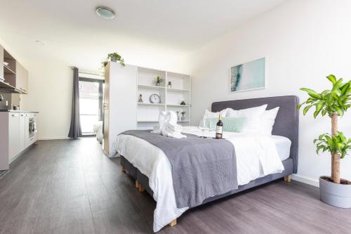 a bedroom with a large bed with white walls at Family executive Studio with Balcony open Delft Utopia Flora 20F in Delft