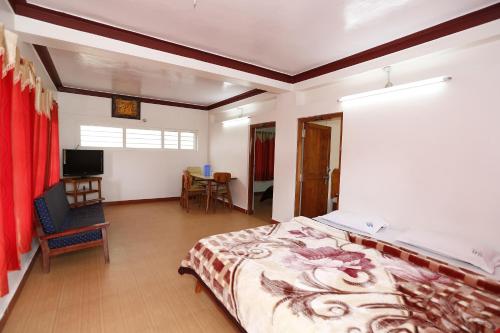 a bedroom with a bed and a chair and a table at Hotel Sri Balaji in Ooty