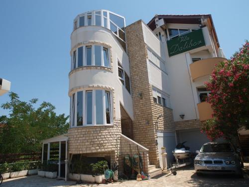 a building with a car parked in front of it at Apartments and bungalows vila Dalibor in Nin