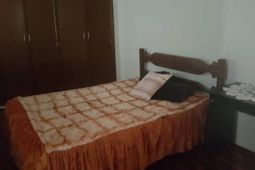 a bed with a quilt and a pillow on it at Apartamento para 6 pessoas in Três Corações