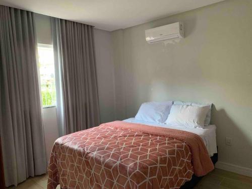 um quarto com uma cama e uma janela com ar condicionado em Apt novo (com ar condicionado) Santa Teresa - ES em Santa Teresa