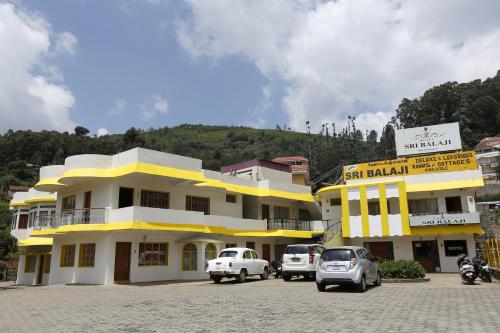 a building with cars parked in front of it at Hotel Sri Balaji in Ooty