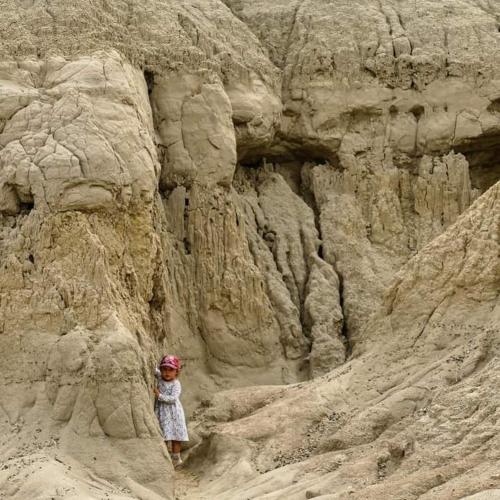 a woman standing in the sand next to a cliff at Hostal Makesa Tatacoa in Villavieja
