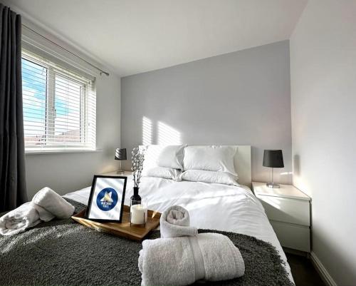 ein weißes Schlafzimmer mit einem Bett und einem Tisch mit einem Bild in der Unterkunft Middlebeck House by Blue Skies Stays in Middlesbrough