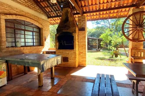 une grande terrasse avec une cheminée en pierre et une table en bois dans l'établissement Refugio na Natureza, à Ribeirão Preto