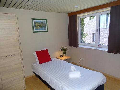 una camera da letto con un letto con un cuscino rosso e una finestra di Room in Studio - Condo Gardens Leuven - Budget Studio Single a Lovanio