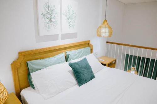 Un dormitorio con una cama blanca con almohadas verdes y blancas en Casa Amarta - Canggu, en Canggu