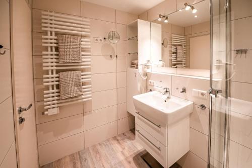 ein weißes Bad mit einem Waschbecken und einer Dusche in der Unterkunft Haus Nordseeblick Nordseeblick, 1 in Norderney