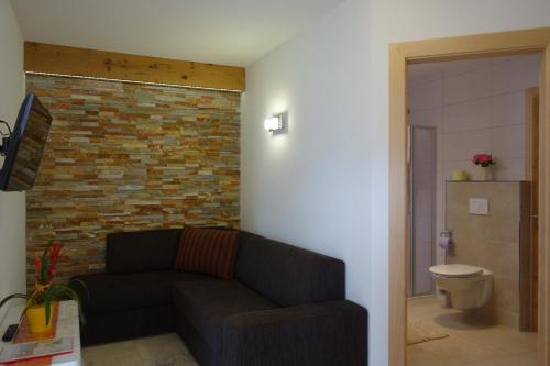 a living room with a couch and a brick wall at Landhaus Dangl in Fliess