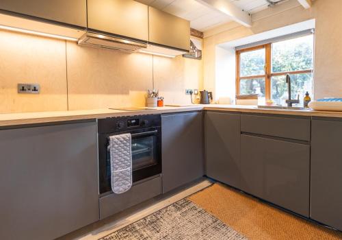 a kitchen with stainless steel appliances and a window at Ty Newydd - a scandi inspired cottage in Moylgrove