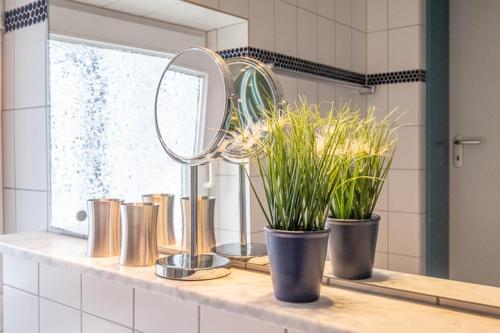 a bathroom counter with two potted plants and a mirror at Haus Regina Maris, Wohnung 7 in Norderney