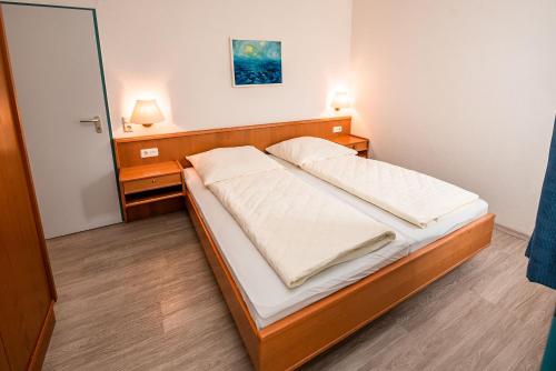 a bed in a bedroom with two lights on at Haus Regina Maris, Wohnung 7 in Norderney