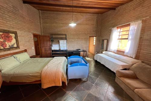 a bedroom with two beds and a couch and a desk at Estância Village de Cunha in Cunha