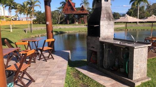 a outdoor grill with tables and chairs next to a river at Chalé Caiçara in Caraguatatuba