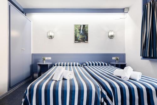 a bedroom with a striped bed with towels on it at El Trull Apartaments in Lloret de Mar