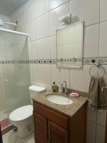 a bathroom with a sink and a toilet and a mirror at Casa em Cond. a 80m da Praia do Peró in Cabo Frio