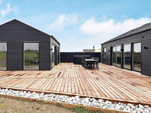 a wooden deck next to a black house at 5 star holiday home in Løkken-By Traum in Løkken