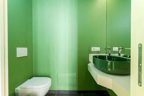 a green bathroom with a sink and a toilet at Le Texture Premium Rooms Duomo-Cordusio in Milan
