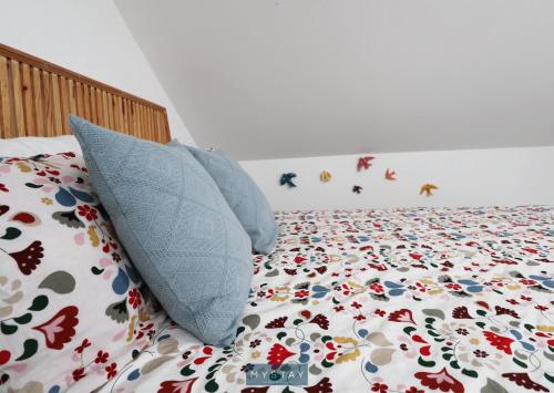 a bed with blue pillows and a comforter with butterflies on it at MyStay - Cantinho do Açor in Vale de Açor