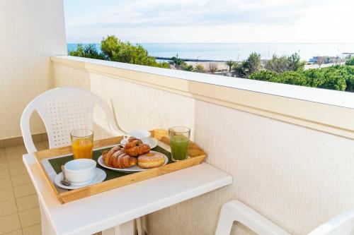 ein Tablett mit Frühstücksspeisen auf einem Sims auf einem Balkon in der Unterkunft Hotel Club La Villa in Martinsicuro