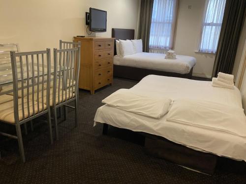 a bedroom with two beds and a dresser and a tv at Grand Plaza Serviced Apartments in London