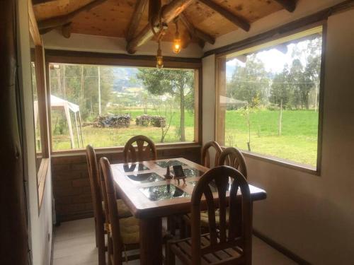 una sala da pranzo con tavolo, sedie e finestra di Cabaña Rumiwasi Imbabura a Otavalo