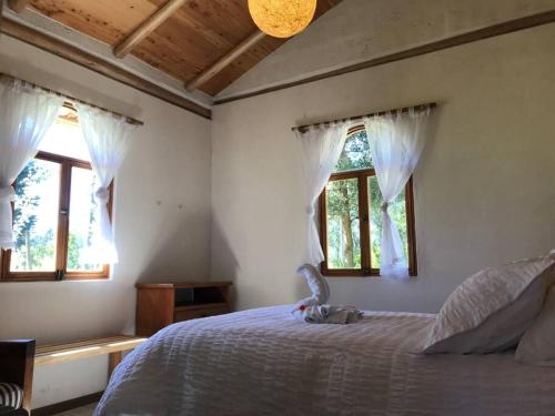 a bedroom with a bed and two windows at Cabaña Rumiwasi Imbabura in Otavalo