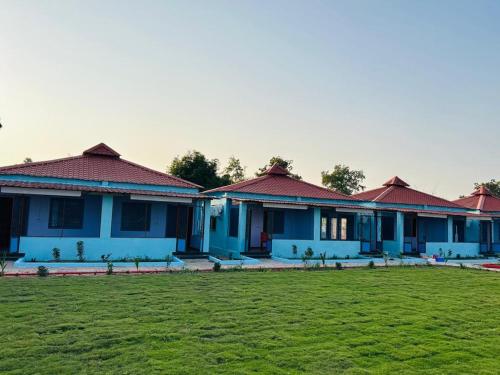 a row of blue houses with a green field at Vrundavan home stay and Village resort in Kevadia