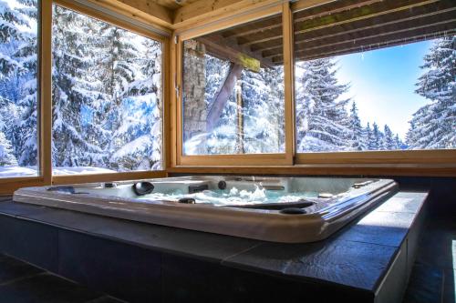 een bad in een kamer met sneeuw bedekte bomen bij Chalet Krystal in Les Carroz d'Araches