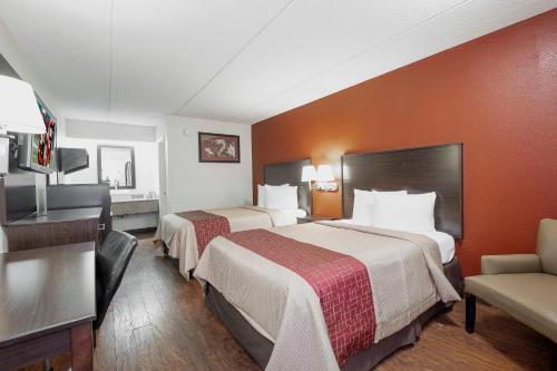 a hotel room with two beds and a desk at Red Roof Inn Jackson North – Ridgeland in Ridgeland